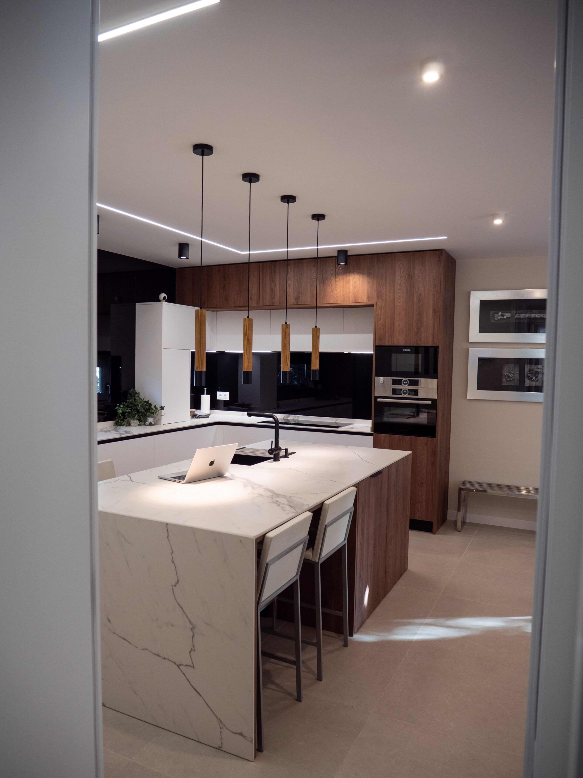 Cocina a medida con hornos integrados en una columna de madera a la altura de la vista